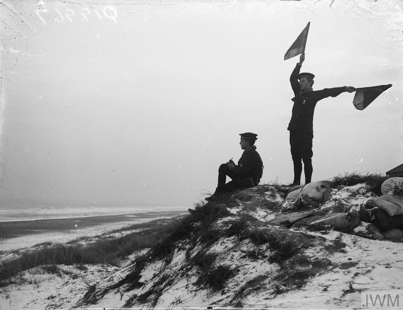 A member of the Sea Scouts taking messages and semaphoring to a Torpedo Boat Destroyer at sea